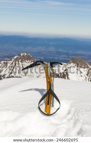 Ice axe stuck in the snow on a background of mountains.