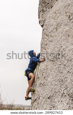Climber glued to the surface of the rock. Looking for another good tricks to go the way of climbing.