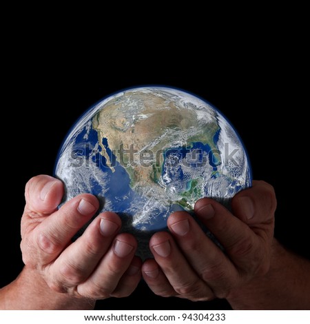 Hands holding world with isolated black background. Earth image courtesy of NASA.