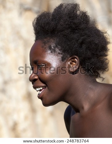 DAMARALAND, NAMIBIA, SOUTH AFRICA.  30 MARCH 2012: Head portrait of a young black woman from the tribe of Damara, who smiles and looks into the distance.