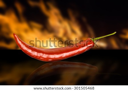 Red hot chili pepper on fire black background