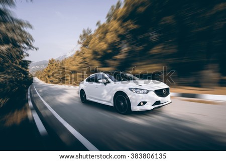 Crimea, Russia - September 20, 2015: White car Mazda speed driving on asphalt road at daytime