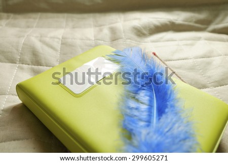 blue feather with green note book , still life style