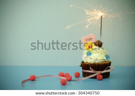 Cupcake with sparkler on blue background , vintage tone