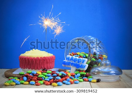 Birthday cake decorated with a sparkler on blue background