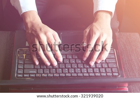 male hands typing on laptop keyboard, freelancer man working with digital computer, filtered image, cross process, flare sun light