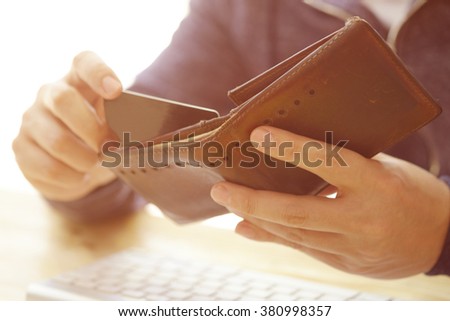 Man\'s hands holding a credit card in wallet and wireless computer keyboard , color filter image , business concept ,business idea