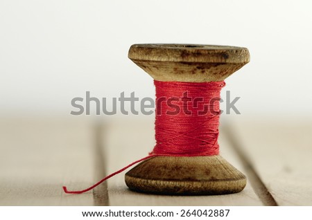 Old spool of thread with needle closeup.  Tailor's work table. textile or fine cloth making.