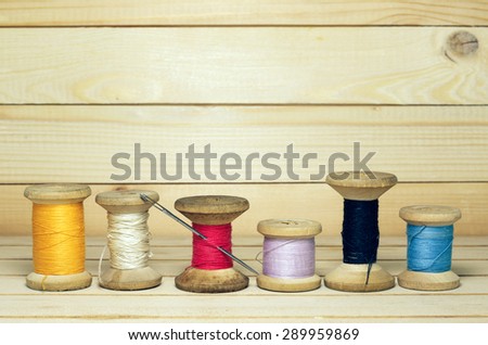 Old spool of thread with needle closeup. Tailor\'s work table. textile or fine cloth making.