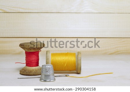 thimble and needle.Old spool of thread with needle closeup. Tailor\'s work table. textile or fine cloth making.