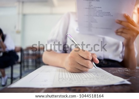 Students writing and reading exam answer sheets exercises in classroom of school with stress.