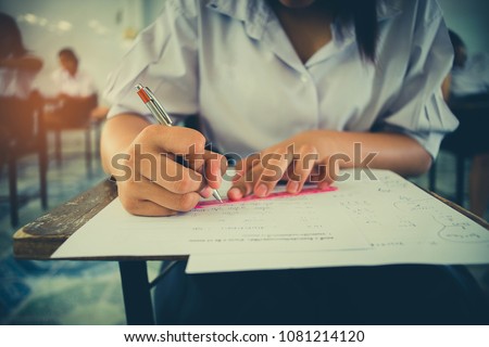 Close up Students writing and reading exam answer sheets exercises in classroom of school with stress.