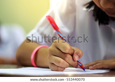 Close-up of writing hands of uniform students at course.