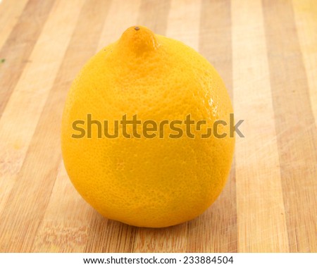 Yellow lemon sit on a worn butcher block cutting board