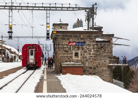 Alp Grum, Switzerland - December 13, 2014 - The sightseeing train Bernina Express stopped at the mountain station Alp Grum with view point to the Palu lake. Tourists got off the train and took photos.