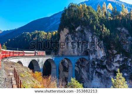 The train of  Rhaetian Railway running on the famous Landwasser Viaduct into the tunnel, on a sunny autumn day, Canton of Grisons, Switzerland