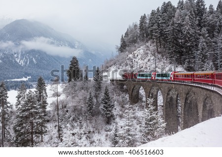 Famous sightseeing train running over viaduct in Switzerland, the Glacier Express in winter