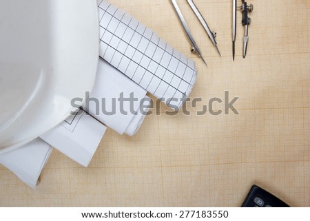 Architectural blueprints, blueprint rolls, compass divider, calculator, white safety on graph paper. Engineering tools view from the top. Copy space. Construction background