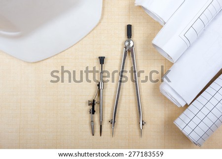 Architectural blueprints, blueprint rolls, compass divider, white safety on graph paper. Engineering tools view from the top. Copy space. Construction background