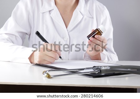 Young woman physician with stethoscope prescribing treatment to patient. Female doctor with pen writing recipe on clipboard in hospital.