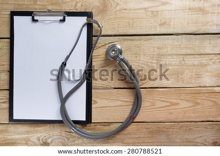 Stethoscope and clipboard on wood table top view . Medical background. Concept for diet, healthcare, nutrition or medical insurance