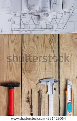Architectural project, blueprints, blueprint rolls and hammer, divider compass, calipers, model knife on vintage wooden background. Construction concept. Engineering tools top view. Copy space
