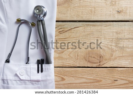 Doctor lab white coat pocket with pen, stethoscope, close-up shot on vintage wooden background. Copy space