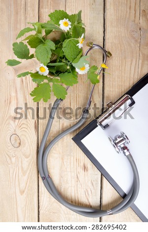 Fresh herb, medical clipboard and stethoscope on wooden table. Alternative medicine concept. Top view.