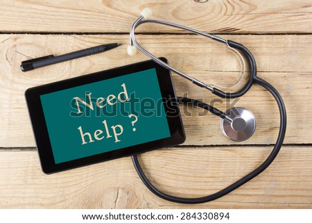 Need help ? - Workplace of a doctor. Tablet, medical stethoscope, black pen on wooden desk background. Top view