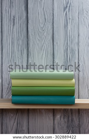 Stack of colorful books and green apple on wooden shelf. Back to school. Copy space