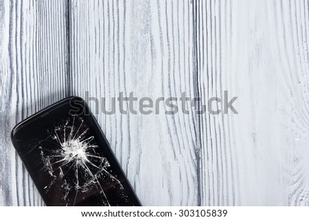 Modern broken mobile phone on white wooden background. Copy space. Top view
