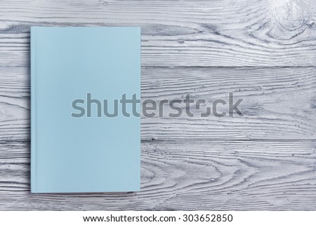 Blank book cover on textured wood background. Copy space