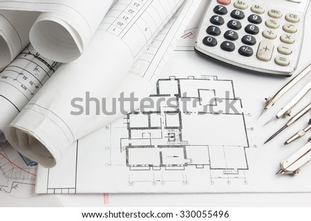 Workplace of architect - Architectural project, blueprints and calculator, divider compass on plans. Engineering tools view from the top. Construction background.