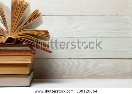 Open book, stack of colorful hardback books on wooden table. Back to school. Copy space for text