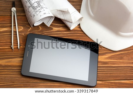 Workplace of architect - Architectural project, plan, blueprint rolls and blank tablet pc, divider compass, safety helmet on table. Civil Engineering or Construction background. Copy space for text