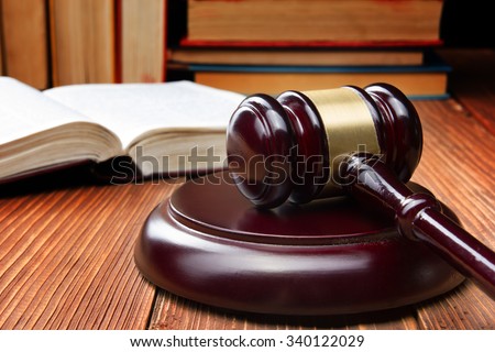 Law concept - Open law book with a wooden judges gavel on table in a courtroom or law enforcement office.