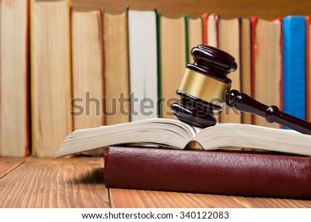 Law concept - Open law book with a wooden judges gavel on table in a courtroom or law enforcement office.