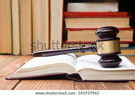 Law concept - Open law book with a wooden judges gavel on table in a courtroom or law enforcement office. Copy space for text