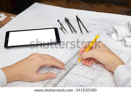 Architect working on blueprint. Architects workplace -  architectural project, plan, drawing, sketch, ruler, blank tablet pc or smartphone, divider compass, pencil. Engineering tools