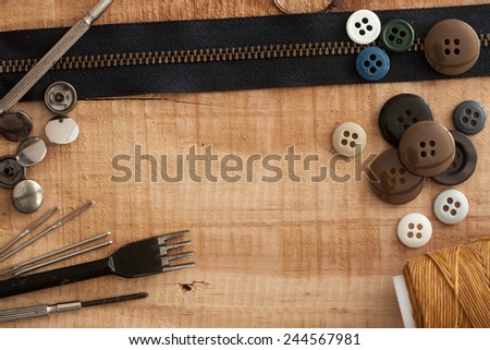 buttons, zipper  and tool on wood background