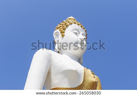White   statue  of   Buddha   on     the   golden   outer robe of a Buddhist priest    shown   on  fresh   clear   blue   sky.