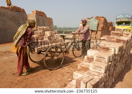 DHAKA, BANGLADESH - FEBRUARY 19, 2014: Two unidentified workers move bricks at a brick factory on February 19, 2014 in Dhaka, Bangladesh. In Bangladesh women often attend very hard jobs.