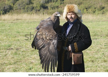 CIRCA ALMATY, KAZAKHSTAN - SEPTEMBER 18, 2011: Unidentified Mongolian hunter in traditional dress holds golden eagle on September 18, 2011 circa Almaty, Kazakhstan.