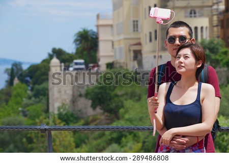 MONACO, MONACO - JUNE 16, 2015: Unidentified asian couple make selfie with a smartphone on a stick at the viewpoint in Monaco.