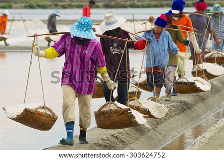 HUAHIN, THAILAND - MAY 13, 2008: Unidentified people carry salt at the salt farm in Huahin, Thailand. Salt production is one of the main industries in Huahin area.