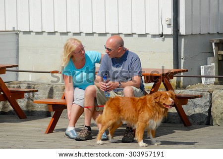 DROBAK, NORWAY - JULY 08, 2006: Unidentified people with a dog rest at the bench in Drobak, Norway.