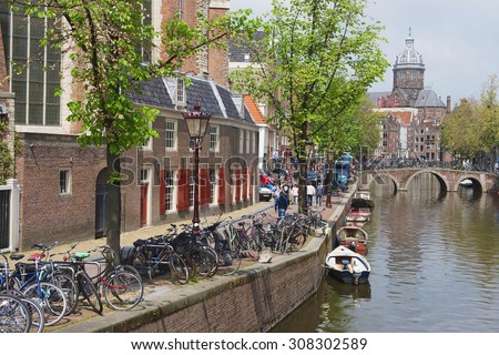 AMSTERDAM, NETHERLANDS - MAY 30, 2013: View to the canal with bicycles parked and basilica of Saint Nicholas at the background in Amsterdam, Netherlands.