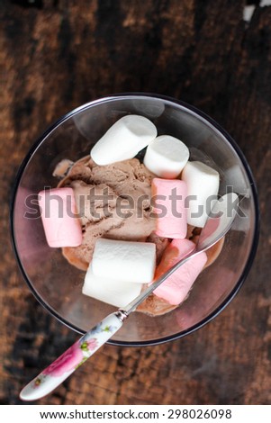 Chocolate Ice Cream with colorful marshmallow in a glass bowl decorate with flower.