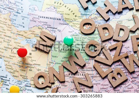 Global map with straight pin and wooden alphabet.