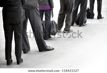 People in dark clothes with bags waiting in queue